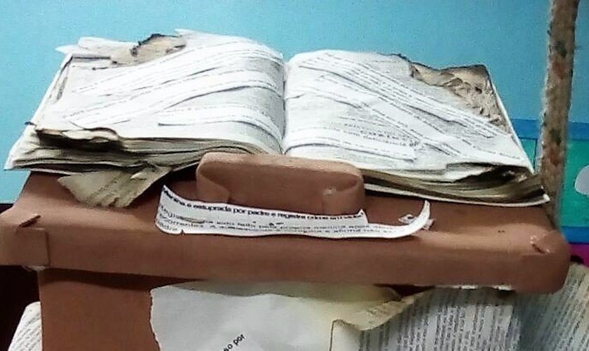 Bíblia queimada com manchetes de abusos sexuais cometidos por pastores e padres coladas, em exposição no Paraná