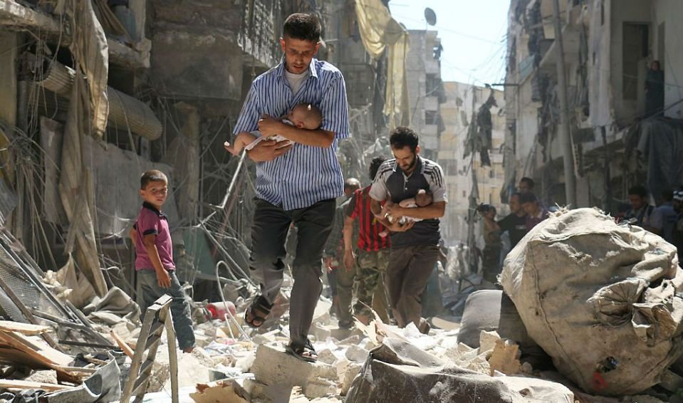 Homens carregam bebês em meio aos escombros, após ataque aéreo na Síria
