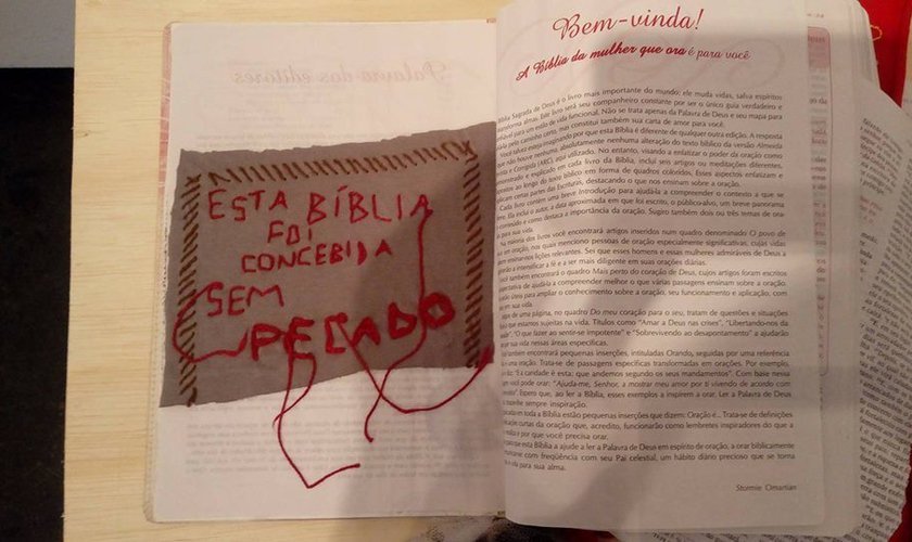 Bíblia rasgada com inscrição sarcástica colocada sobre ela, em exposição na UFPE