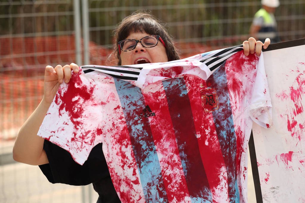 Militante da causa palestina protesta e mostra camisa da seleção pintada de vermelho em frente ao CT do Barcelona, durante treino da seleção argentina