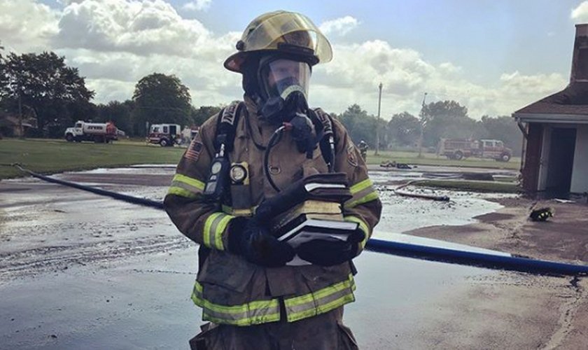 Bombeiro segura as Bíblias que foram resgatadas intactas do incêndio.