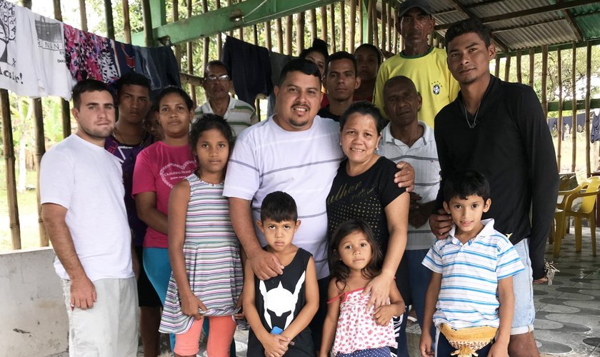 Gedeão (no centro) ao lado da esposa, Sandra, e parte dos refugiados que acolheram. (Foto: Emily Costa/G1 RR)