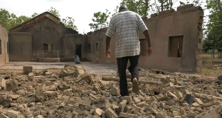 Pastor caminha em frente a sua igreja destruída pelos fulanis, na Nigéria (Foto: Portas Abertas)