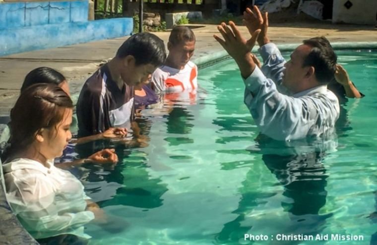 Um pastor batiza novos cristãos convertidos na Indonésia.