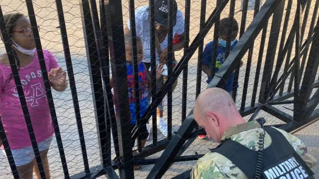 O soldado Dan Otterson (de farda) se ajoelhou, enquanto o garoto de 5 anos orou por ele, do outro lado da cerca. (Foto: Facebook)