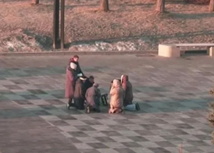 Ucranianos se ajoelham para orar em uma praça após ataques da Rússia