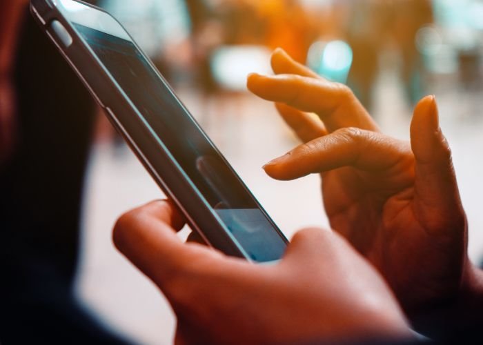 Mãos de uma mulher segurando um smartphone (Foto: Canva Pro)