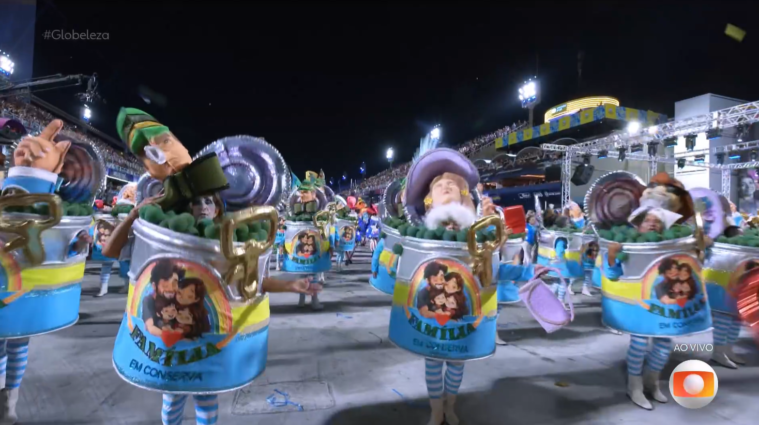 Carro alegórico de escola de samba com representações satíricas de figuras políticas e religiosas em desfile de carnaval.