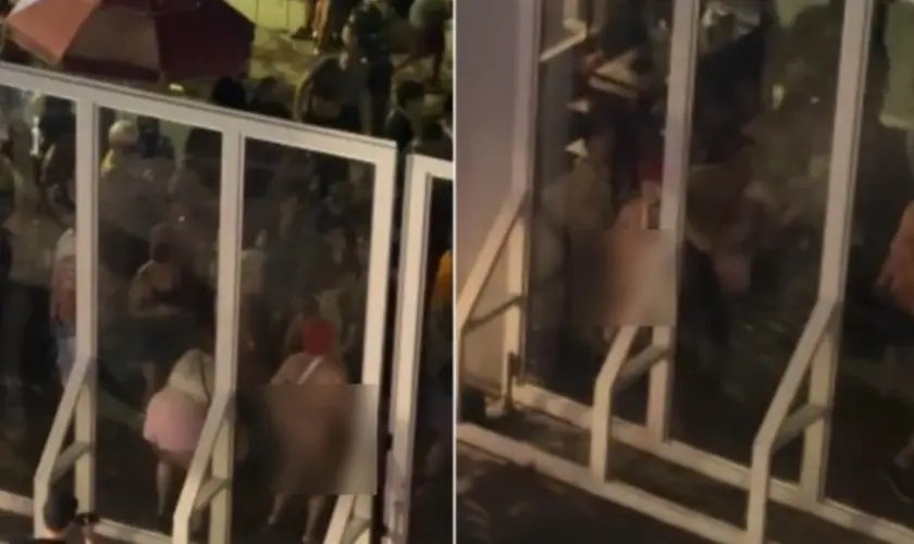 Foliões de bloco de carnaval em BH realizam gestos em frente a uma igreja.