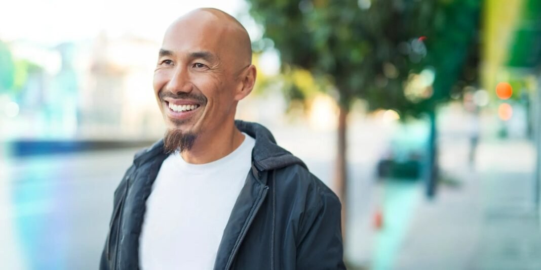 Francis Chan em um ambiente de estudo, segurando uma cópia de seu livro 'Ser Amado'.