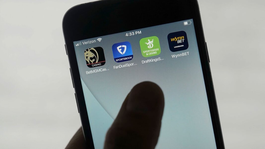 Jovem absorto em aplicativo de apostas esportivas no celular.