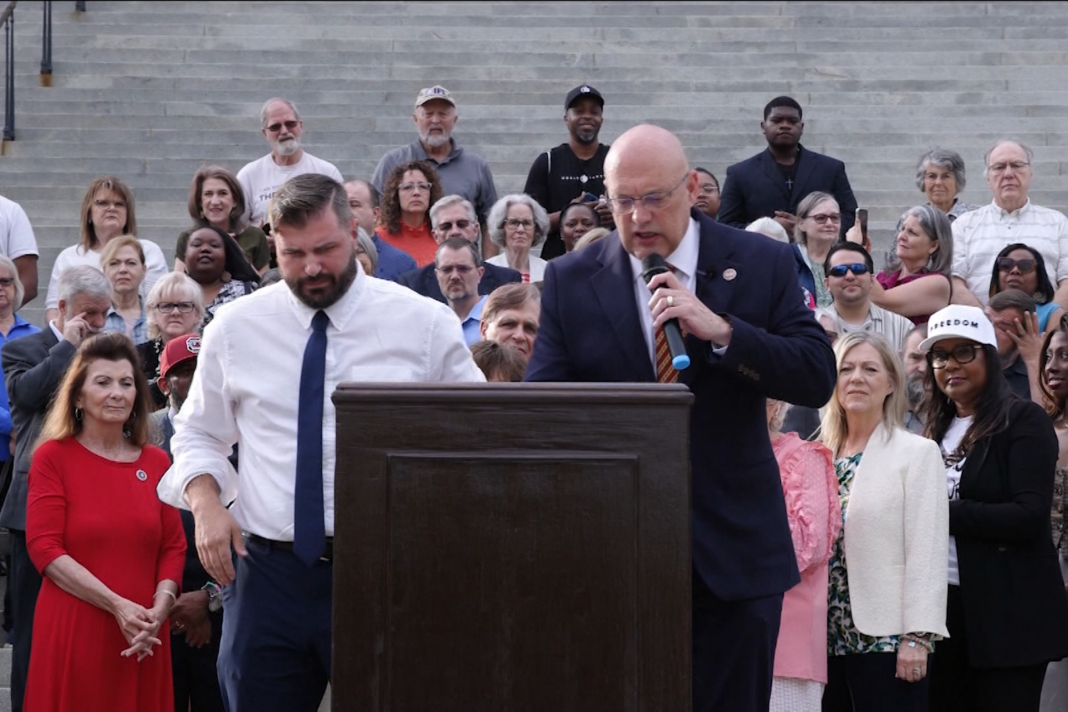 Edifício governamental da Carolina do Sul com cidadãos reunidos em frente, simbolizando união e fé.