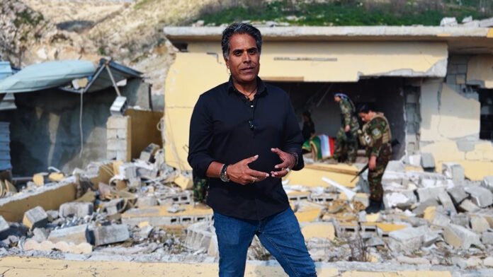 Combatentes curdos em posição defensiva na fronteira Iraque-Irã com destroços ao fundo