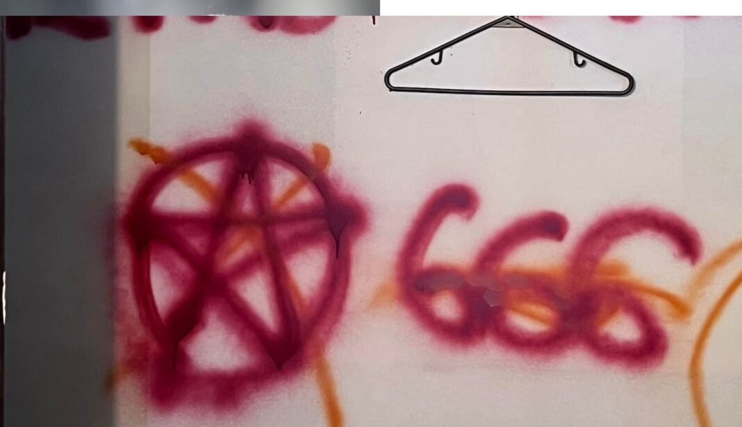 Placa de igreja batista vandalizada com símbolos ocultistas e spray.