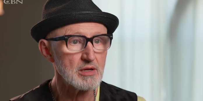 Homem idoso sorrindo, segurando um laudo médico que confirma cura