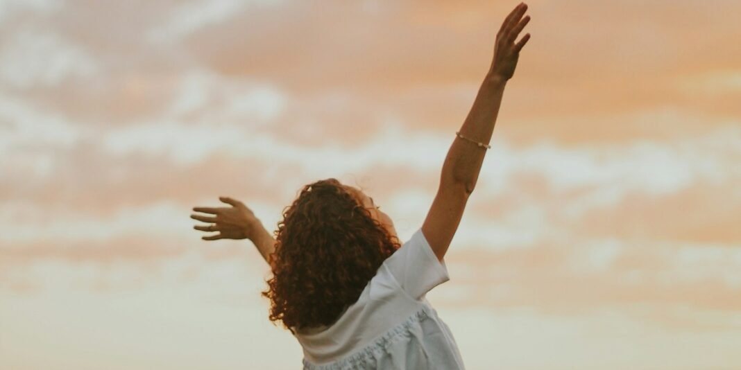 Mulher com expressão serena e esperançosa segurando um livro, sob luz natural.