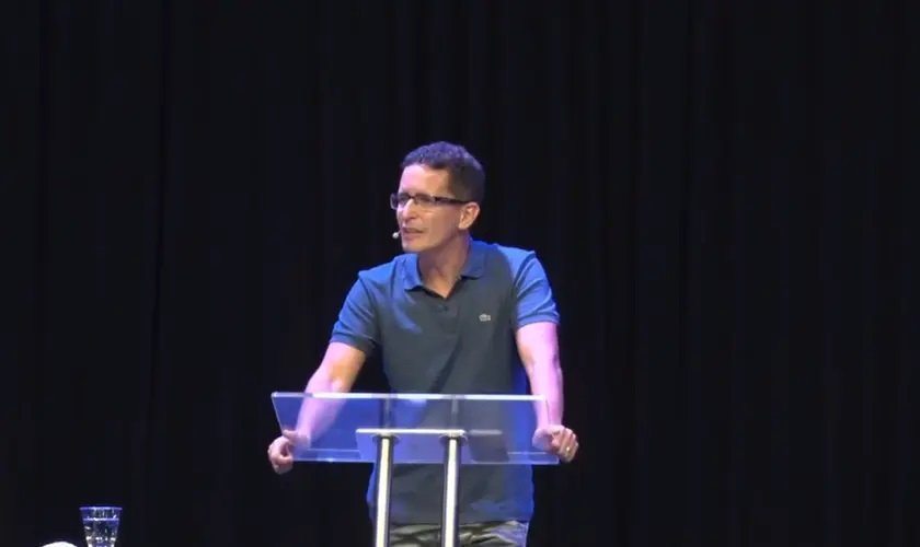 Pastor Edilson de Lira Vasconcelos Filho em um púlpito durante um culto.