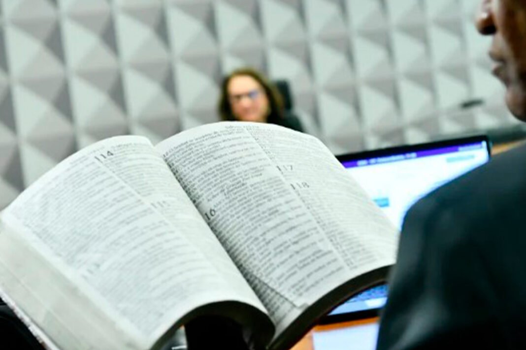 Sala de comissão do Senado Federal com documentos sobre a mesa durante análise de projeto de lei.