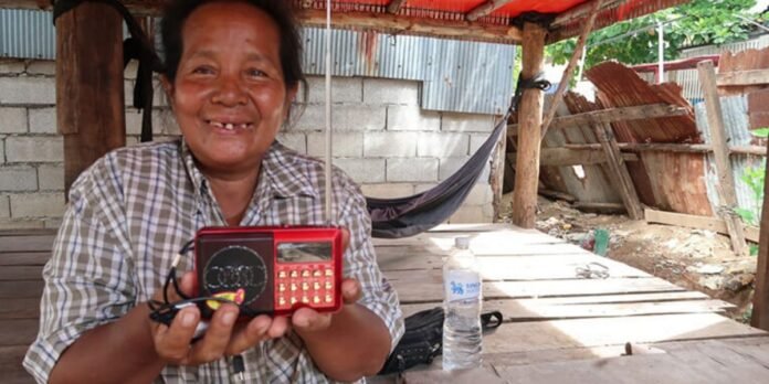 Viúva cambojana sorri em frente à nova casa construída por missão