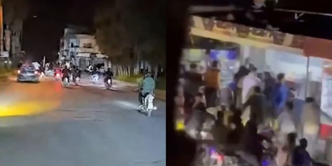Rua em cidade síria com danos visíveis após ataque durante a Semana Santa, com moradores observando e forças de segurança presentes.