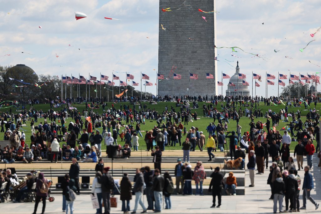 Pessoas diversas reunidas no National Mall em Washington D.C. em um dia ensolarado de primavera.