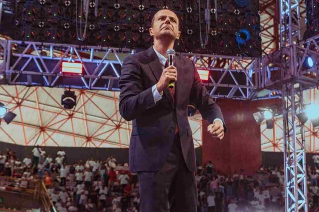 Pastor Juliano Fraga pregando com uma Bíblia em mãos.