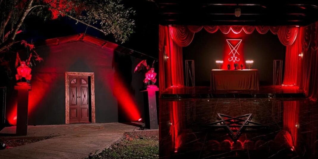 Fachada de um templo de aparência sombria, decorado em vermelho e preto, com elementos que remetem a símbolos satânicos.