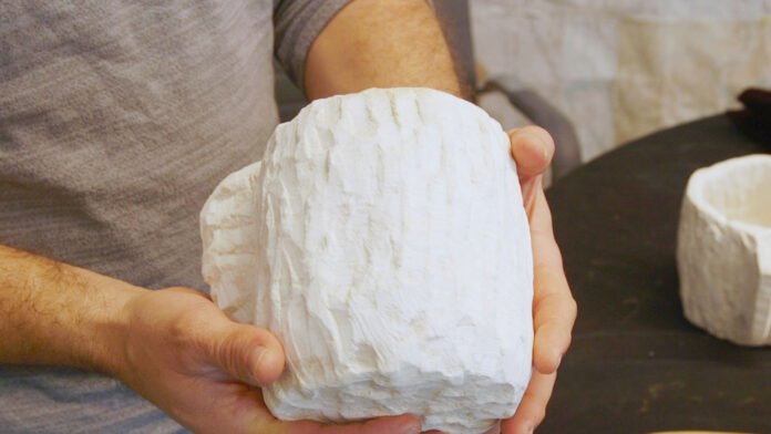 Arqueólogo Dr. Eitan Klein examinando um fragmento de cerâmica em um sítio arqueológico à noite em Israel