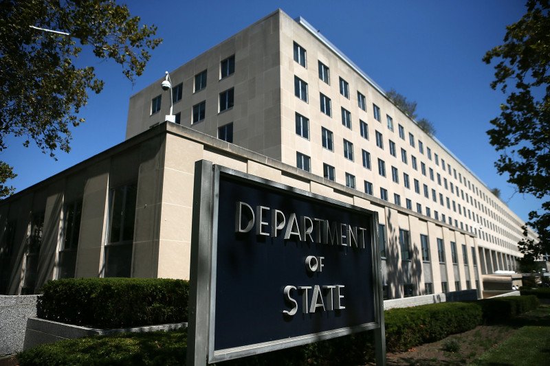 Fachada do Departamento de Estado dos EUA com bandeira americana ao amanhecer