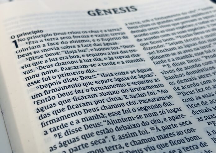 Conflito entre tecnologia e conteúdo religioso na era da IA. Laptop com interface do ChatGPT ao lado de um tablet exibindo o livro de Gênesis.