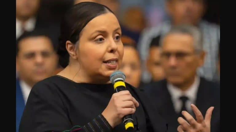 Pastora discursando em palco com telão exibindo Disque 100