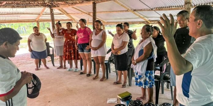 Comunidade rural colombiana reunida em culto na igreja recém-reaberta.