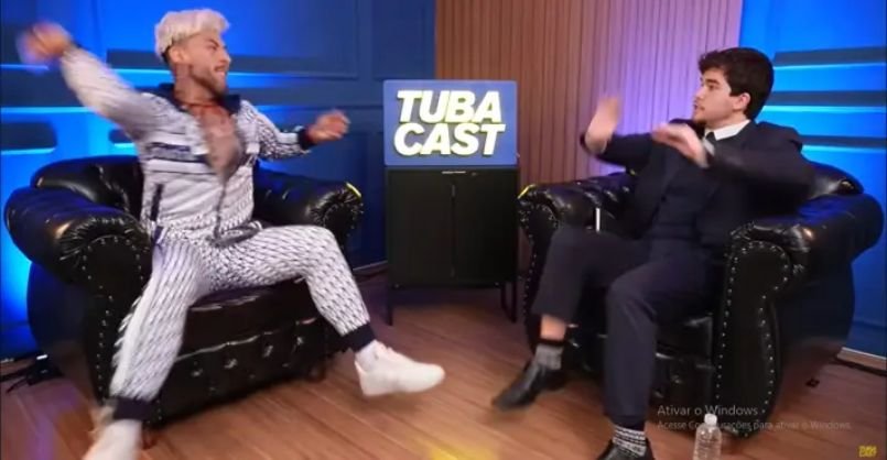 Influenciador ataca oponente com garrafa de água durante debate ao vivo em podcast.