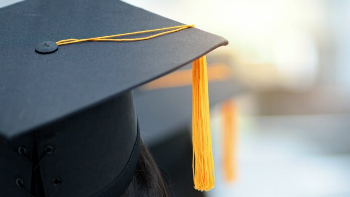 Recém-formado pondera o futuro com diploma e laptop