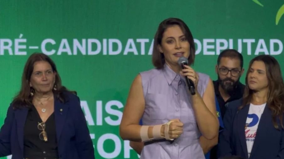 Michelle Bolsonaro em evento político discursando com expressão séria.