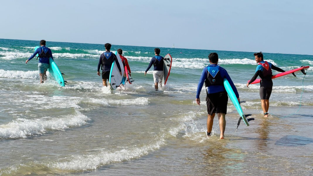 Jovens de diferentes etnias e religiões surfando juntos em Israel como parte de um programa terapêutico.