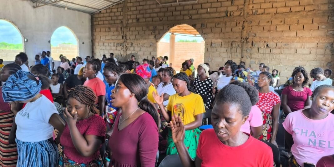 Pastor africano sorrindo com mulheres recém-convertidas em Moçambique.
