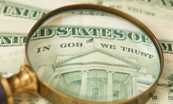 A inscrição 'Em Deus nós Confiamos' em uma nota de dólar. Nota de dólar com a inscrição 'Em Deus nós Confiamos' em destaque.