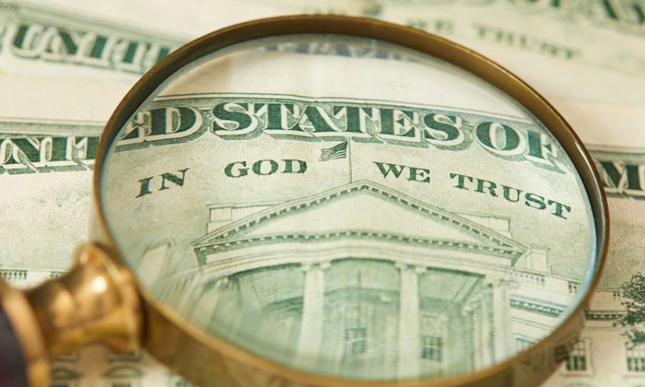 Nota de dólar com a inscrição 'Em Deus nós Confiamos' em destaque.