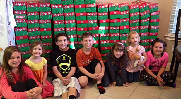 Voluntários organizando caixas de presente de Natal para doação em frente a uma escola