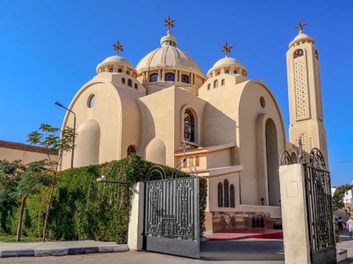 Fachada iluminada de uma igreja cristã no Egito, com pessoas entrando e saindo.