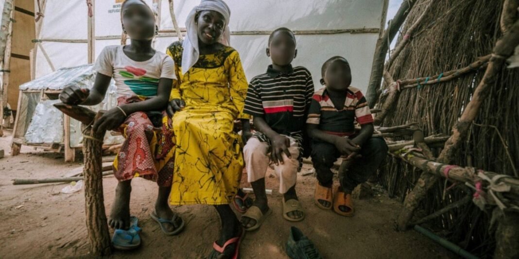 Família nigeriana caminha descalça em área rural após fugir de ataques terroristas.