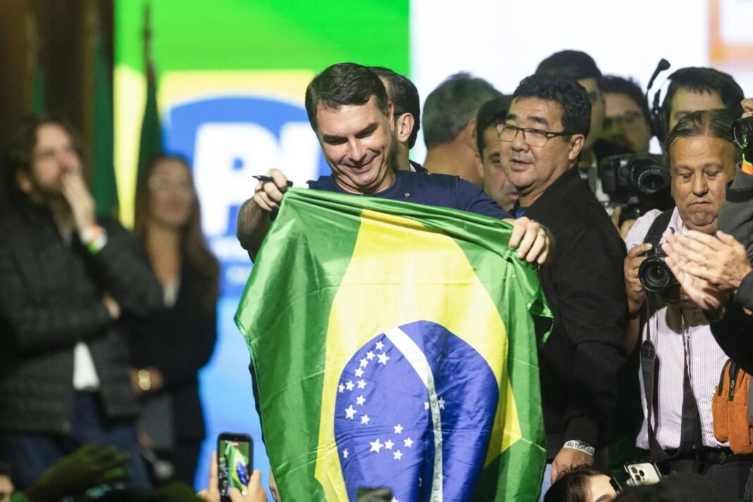 Senador Flávio Bolsonaro discursa em evento religioso com grande público ao fundo.