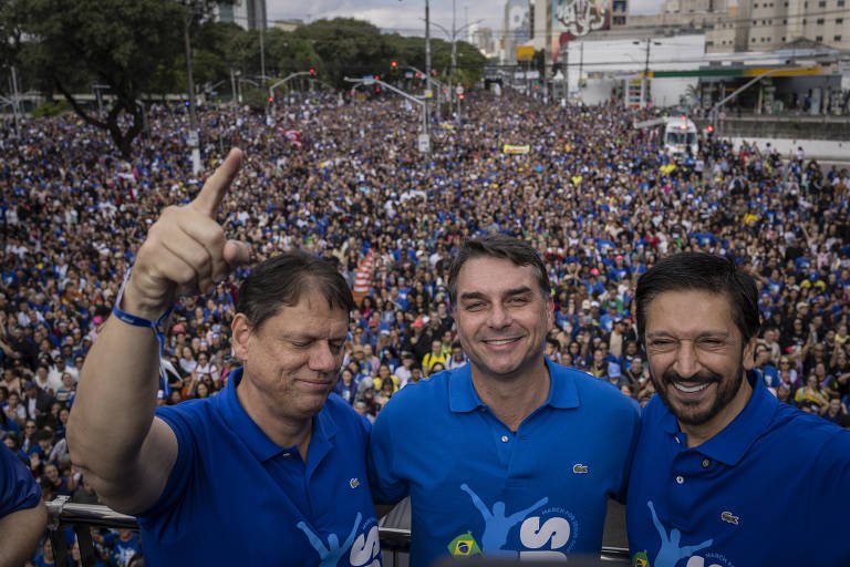 Senador Flávio Bolsonaro em cima de um trio elétrico na Marcha para Jesus em São Paulo, acenando para a multidão.