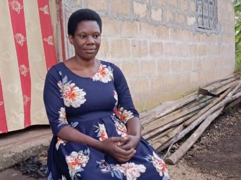 Mulher cristã resiliente em frente a uma igreja danificada na Tanzânia