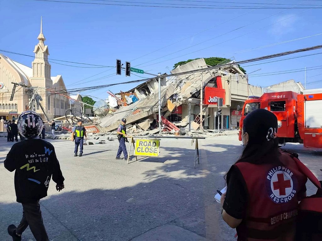 Cidade filipina devastada por terremoto com prédios destruídos e equipes de resgate