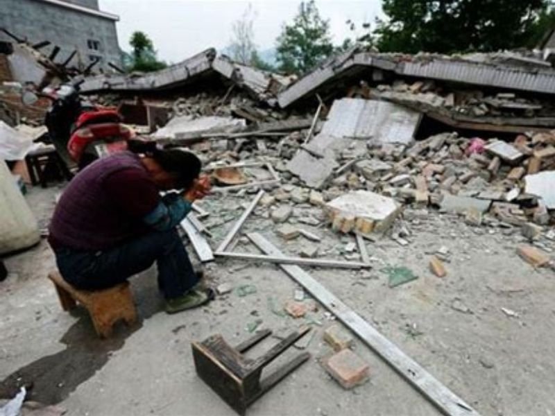 Rua devastada em Mindanao após terremoto, com prédios desmoronados e destroços.