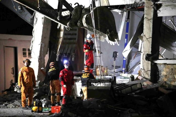 Equipes de resgate procuram sobreviventes em meio aos escombros de um prédio destruído por terremoto nas Filipinas.
