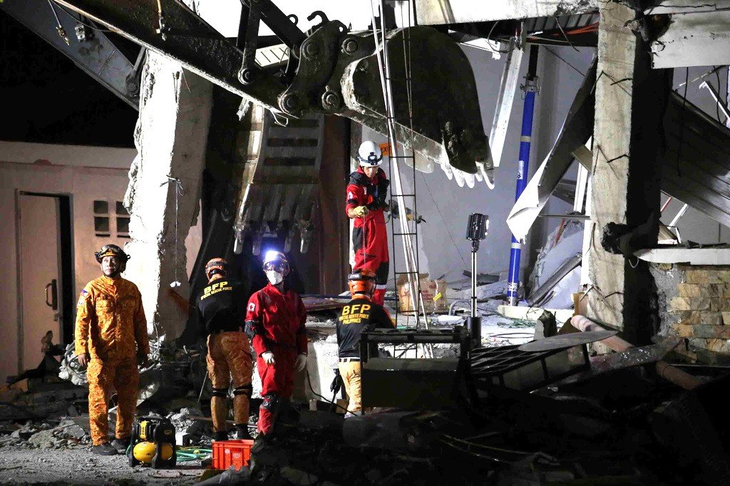 Equipes de resgate procuram sobreviventes em meio aos escombros de um prédio destruído por terremoto nas Filipinas.