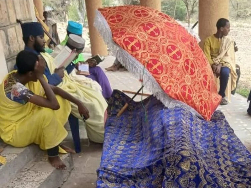 Monastério etíope histórico danificado após ataque aéreo, com fiéis em luto.